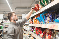 Man with a beard takes a pack of chips from the store shelves ...